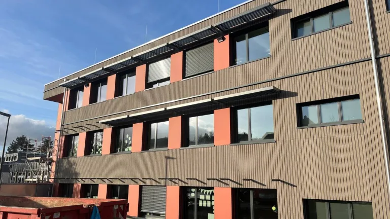 Mehrgeschossige Schulfassade mit horizontalen Sonnenschutzelementen über den Fenstern