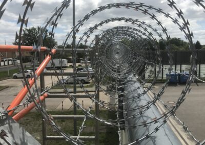 Natodrahtrolle als Nato Draht Übersteigschutz auf Mauer, Montage mit Y-Trägern und Stacheldraht Spanndraht