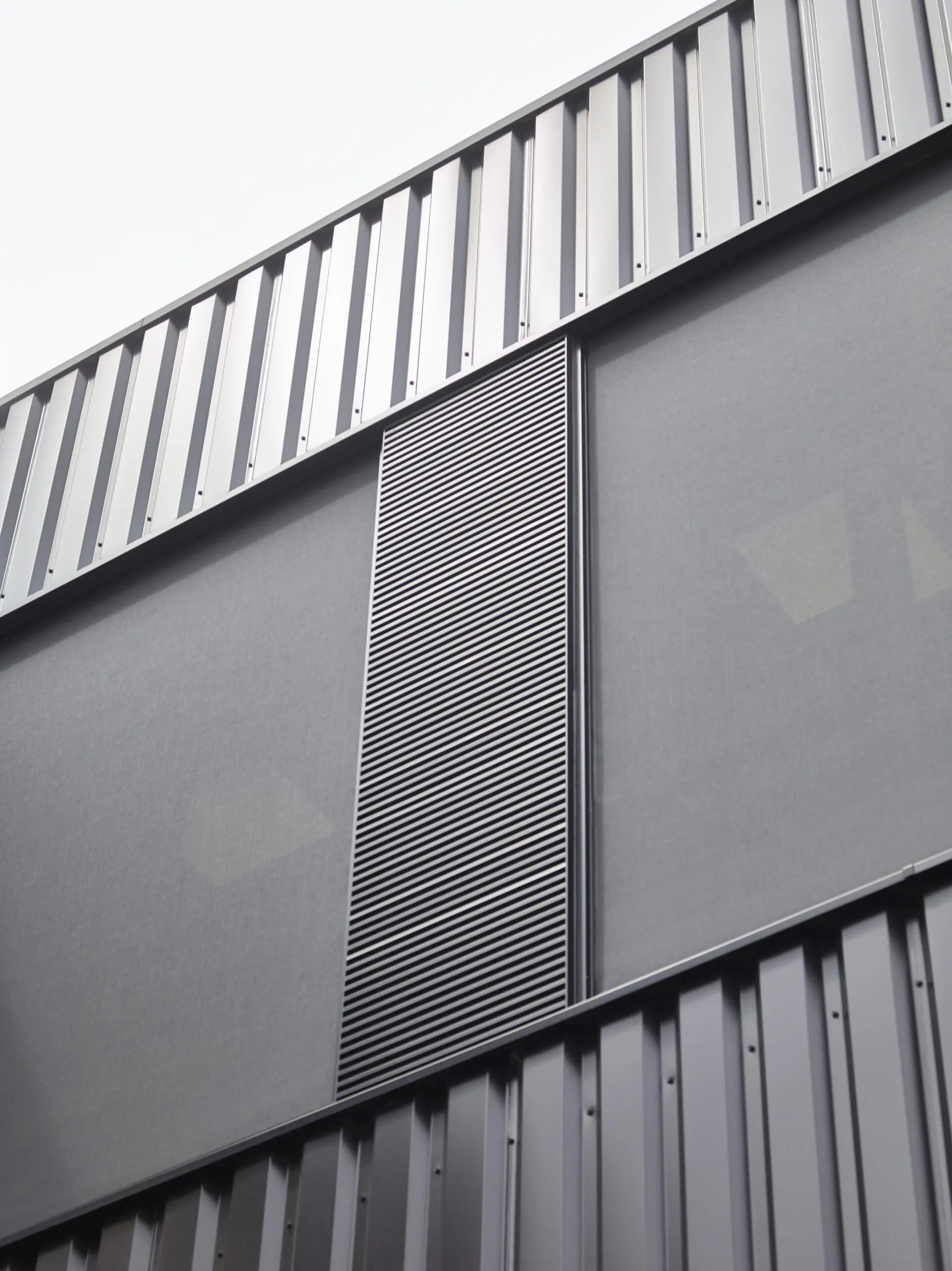 Integriertes Lüftungsgitter in einer technischen Fassade für Nachtauskühlung, Wetterschutz und sichere Luftführung